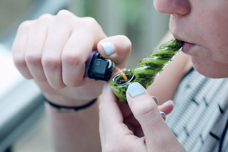 A person holding a lighter up to their pipe