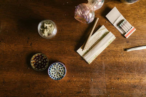 Stoner accessories, including a grinder and pipe, on a wood tabletop	